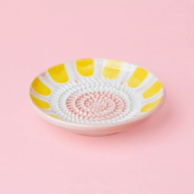 Prato cerâmico pequeno com padrão amarelo e rosa sobre fundo rosa