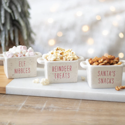 Três recipientes de cerâmica com marshmallows, pipocas e amendoins, com texto vermelho