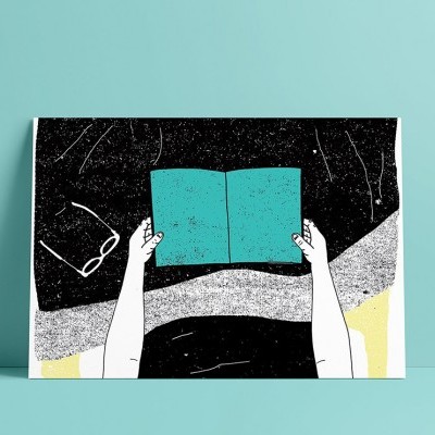 Pessoa segurando livro azul aberto com óculos ao lado