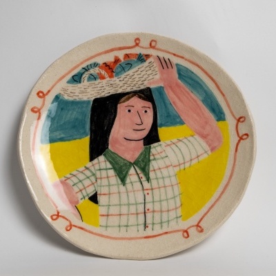 Prato decorativo de cerâmica com desenho de mulher e cesta de frutas