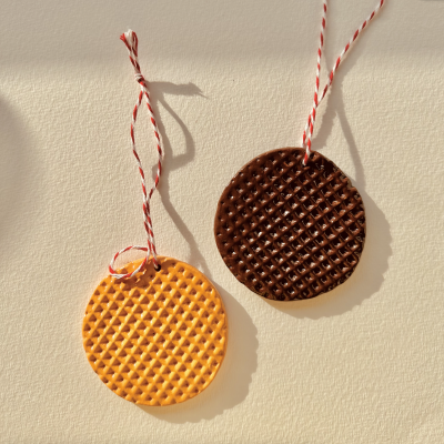 Pendentes redondos amarelo e castanho com textura de waffle pendurados por fios vermelhos e brancos.