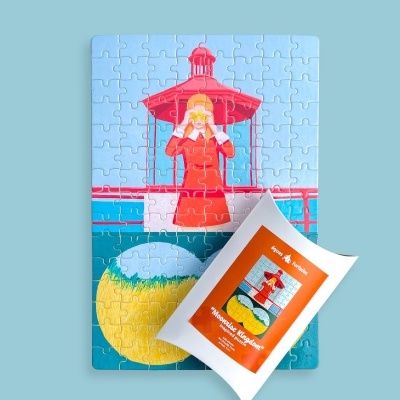 Quebra-cabeças com imagem de farol e mulher, embalagem branca com etiqueta laranja