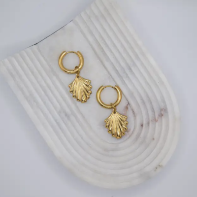 Brincos de argola dourada com pendente em forma de folha sobre suporte branco