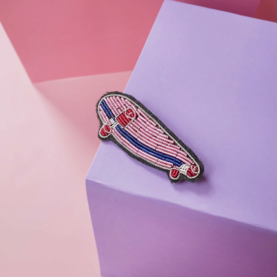 Broche bordado em forma de skate sobre cubo lilás