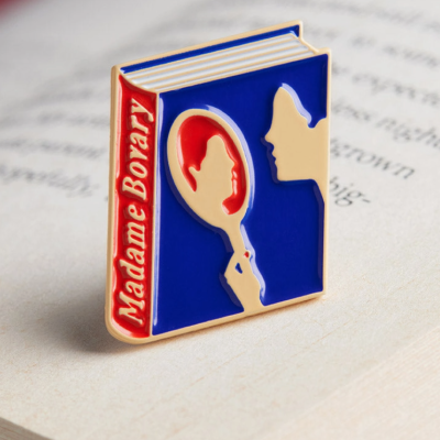 Pin metálico esmaltado em forma de livro Madame Bovary com silhuetas e cores azul, vermelho e bege
