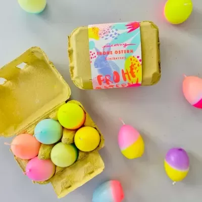 Caixa de ovos coloridos de plástico com etiqueta colorida numa superfície cinza claro