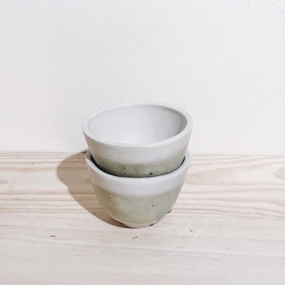 Dois copos de cerâmica branca empilhados sobre fundo branco