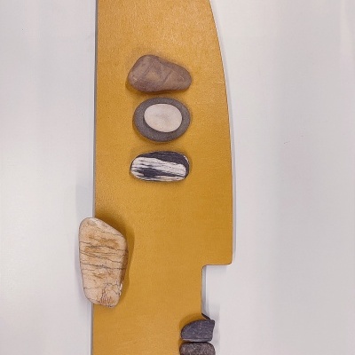 Peça decorativa amarela em forma de faca com pedras naturais em cima