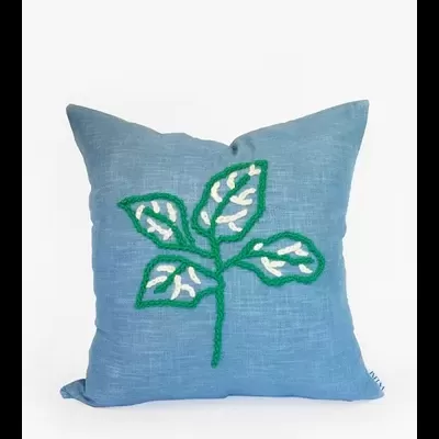 Almofada azul com bordado de folhas verdes e brancas