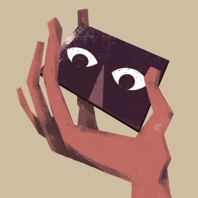 Mão a segurar objeto retangular roxo com olhos desenhados