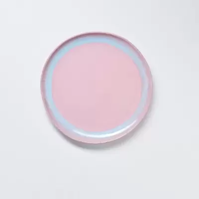 Prato redondo cor-de-rosa com borda azul clara sobre fundo branco