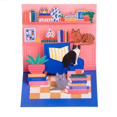 Cena interior ilustrada com gatos, cadeira azul, livros e prateleiras cor-de-rosa