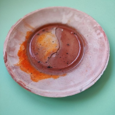 Prato de cerâmica com manchas de líquido sobre superfície verde