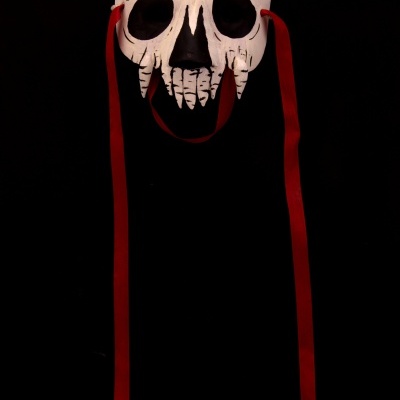 Máscara branca de caveira com detalhes pretos e vermelhos e fitas vermelhas longas.