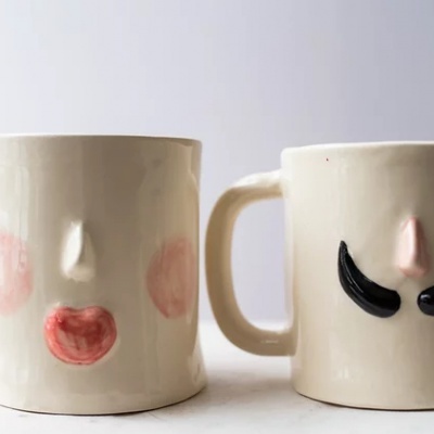 Dois canecas de cerâmica com rostos decorativos