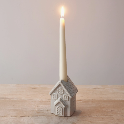 Vela branca alta numa base de casa cinzenta sobre madeira clara