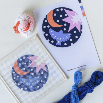 Conjunto de bordado com padrão de pássaro, lua e estrela em tons azul, laranja e lilás com novelos de lã colorida
