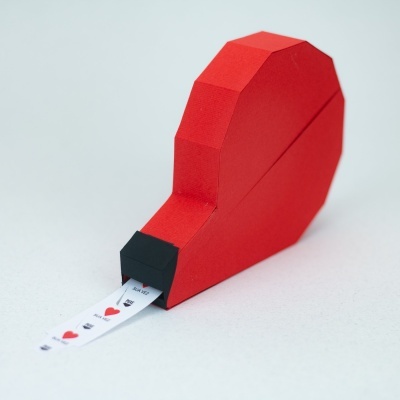 Objeto de papel vermelho com tira branca a sair da extremidade preta