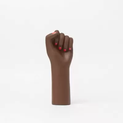 Escultura de punho fechado castanha com unhas vermelhas em fundo branco