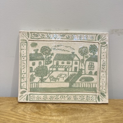 Azulejo cerâmico decorativo com desenho de casas e árvores em verde e bege