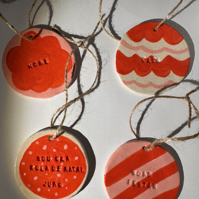 Quatro etiquetas decorativas de madeira em vermelho e rosa com texto e cordões de pendurar