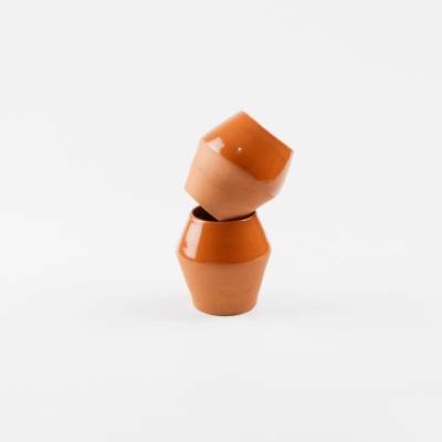 Dois pequenos vasos de barro cor terracota empilhados em fundo branco