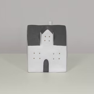 Casa decorativa em cerâmica branca e preta sobre superfície branca