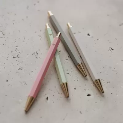Canetas douradas de corpo hexagonal em tons pastel com corações