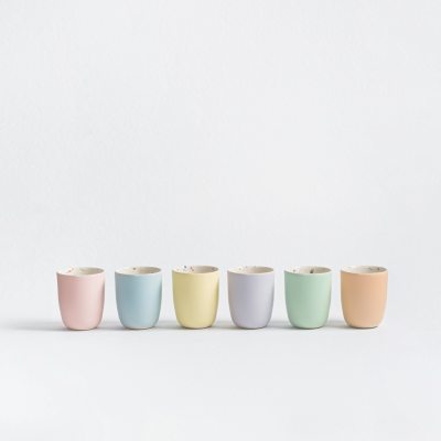 Seis copos pequenos em cores pastel alinhados sobre fundo branco
