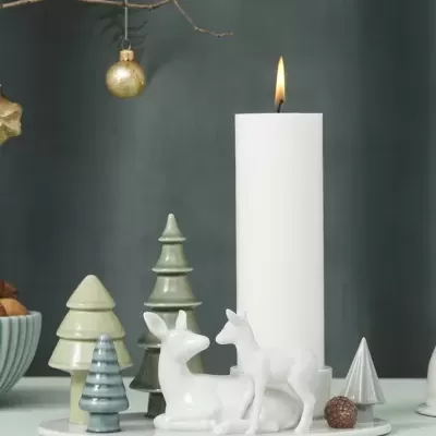 Vela branca decorativa com figuras de veados e árvores de Natal em base branca