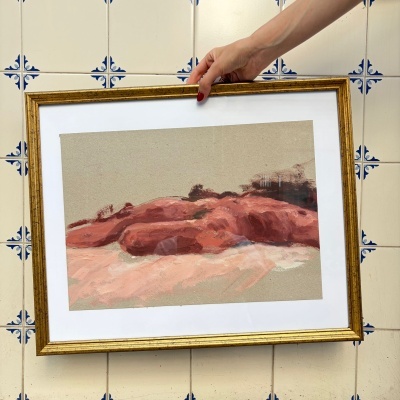 Pintura em moldura dourada segurada por mão contra azulejos