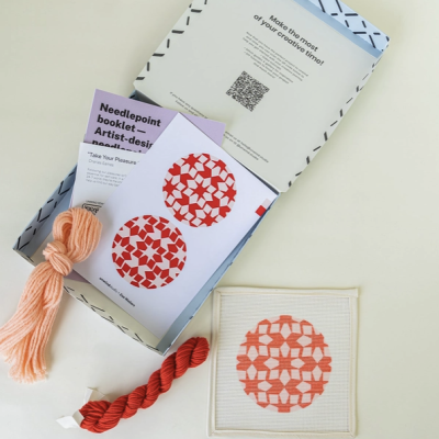 Caixa aberta com material de ponto cruz e padrão geométrico vermelho