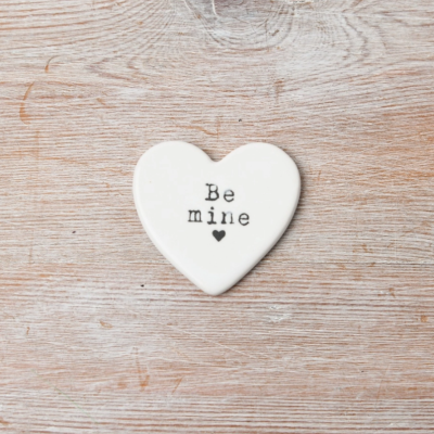 Coração decorativo branco com texto 'Be mine' sobre madeira clara