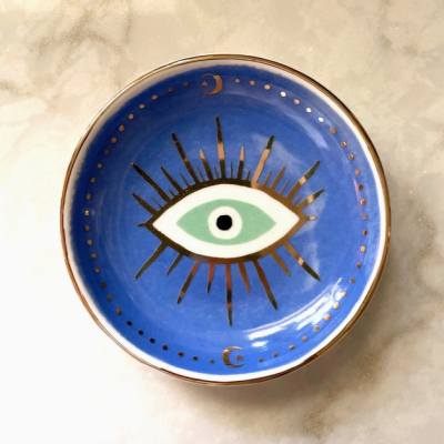 Prato decorativo azul com desenho de olho e detalhes dourados