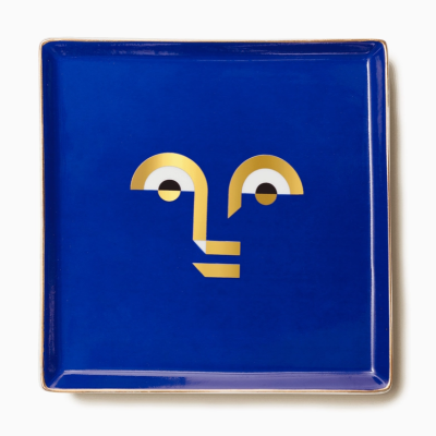 Prato quadrado azul com padrão dourado e branco formando rosto