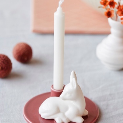 Castiçal cor de rosa com vela branca e coelho decorativo branco em superfície cinza