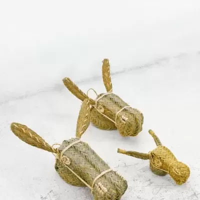 Esculturas de animais trançadas em palha sobre superfície clara