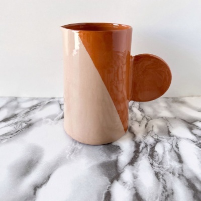 Caneca cerâmica castanha e bege numa mesa marmoreada