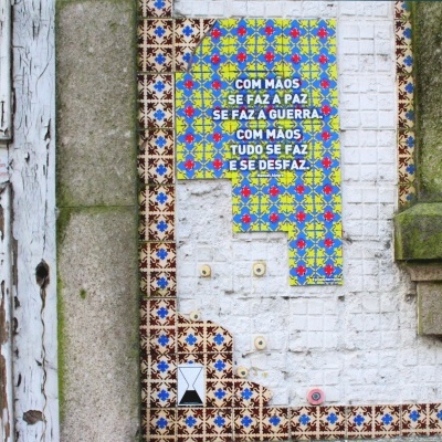 Mosaico com padrão colorido e texto em português numa parede azulejada