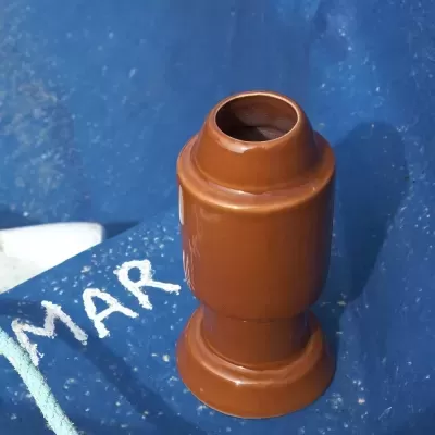 Objeto cilíndrico de cerâmica castanha sobre tecido azul com texto 'MAR'