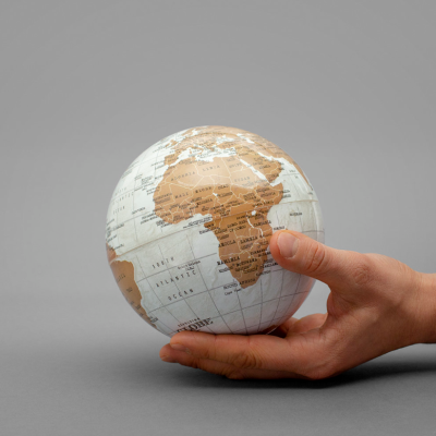 Globo terrestre pequeno com mapa de África segurado por duas mãos