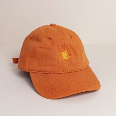Boné de tecido cor de ferrugem com bordado amarelo em forma de sol