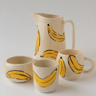 Conjunto de loiça creme com padrão de bananas amarelas.