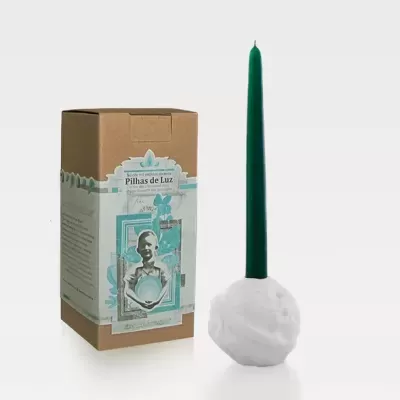Vela verde alta com base branca texturada ao lado da embalagem de cartão com rótulo 'Pilhas de Luz'