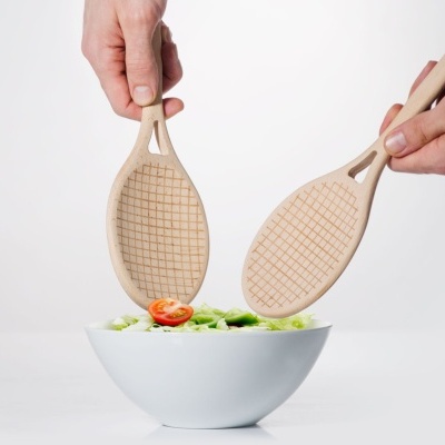 Espátulas de madeira a servir salada numa tigela branca