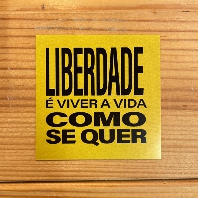 Adesivo amarelo com texto preto sobre madeira clara
