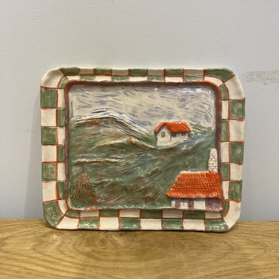 Tabuleiro cerâmico com relevo de paisagem e borda quadriculada verde, creme e vermelha