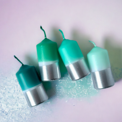 Quatro velas verdes com base prateada sobre fundo rosa com pó branco.