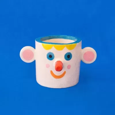 Caneca de cerâmica decorada com rosto sorridente em fundo azul