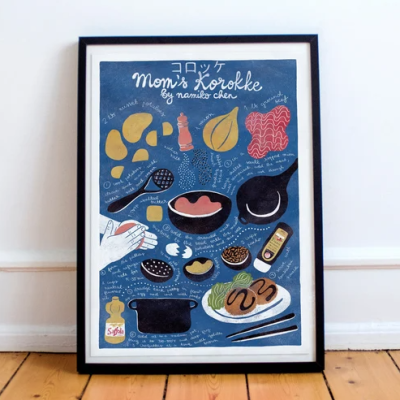 Pôster com receita ilustrada 'Mom's Korokke' com desenhos coloridos de ingredientes e utensílios, em moldura preta sobre chão de madeira